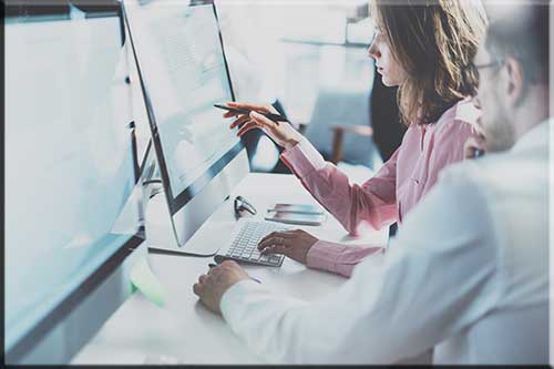 Two people pointing at a computer screen